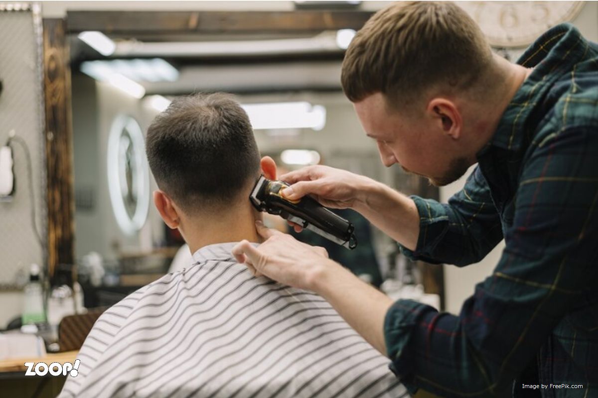 Um barbeiro cortando o cabelo de um cliente ilustra nosso artigo sobre: melhores marcas de máquina de cortar cabelos.