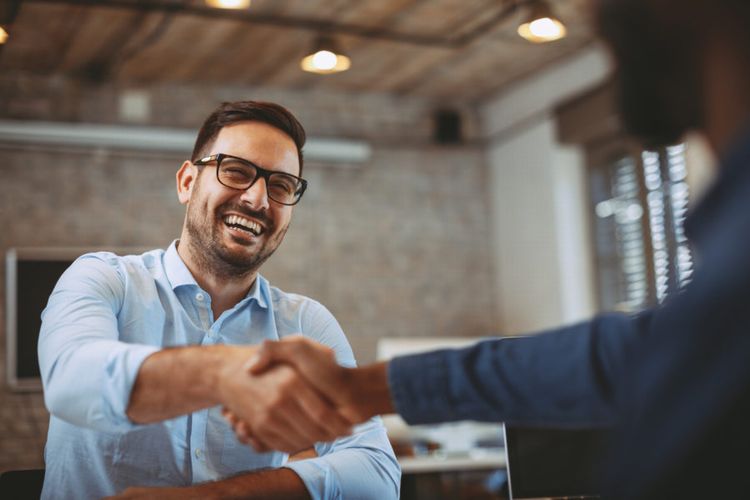 Um vendedor sorridente apertando a mão de um novo cliente.