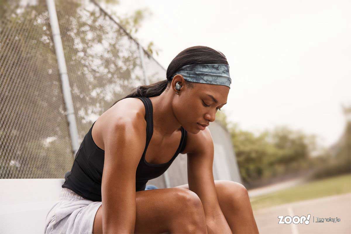 Mulher usando fones de ouvido para corrida da marca Beats Fit Pro.