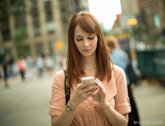 Mulher jovem mexendo no celular.