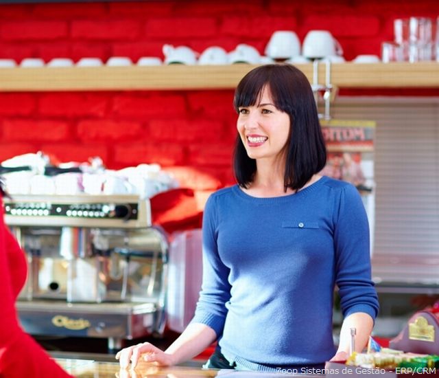 Uma mulher jovem atendendo a um cliente em uma cafeteria.