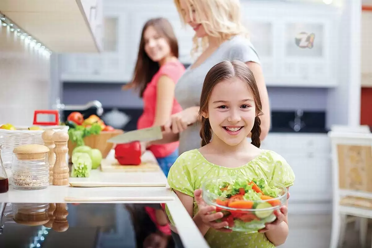 Uma mãe e suas duas filhas cozinhando juntas.