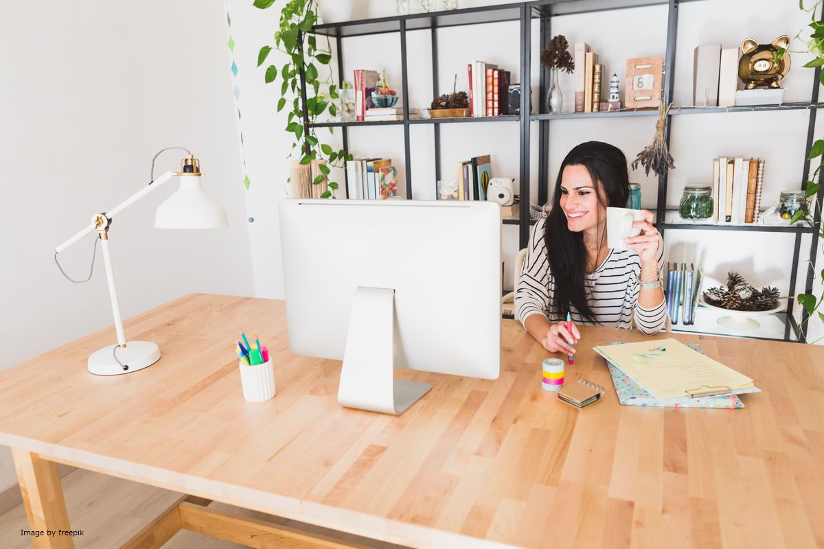 Mulher bebendo café enquanto olha a tela do computador ilustra nosso artigo sobre: Economia digital: o que é e quais o seus pilares.